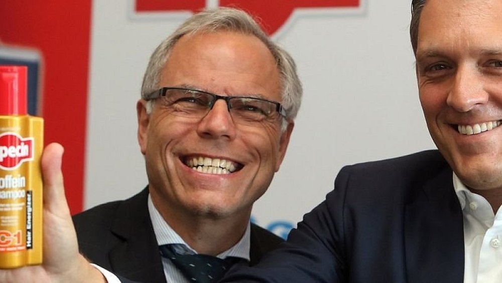 Breites Grinsen vor einer Alpecin-Flasche