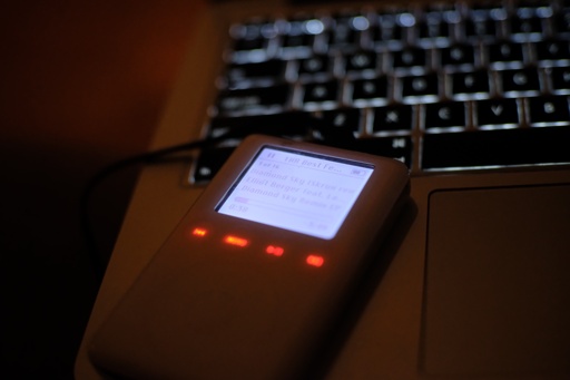 iPod sitting on laptop palmrest in dark room