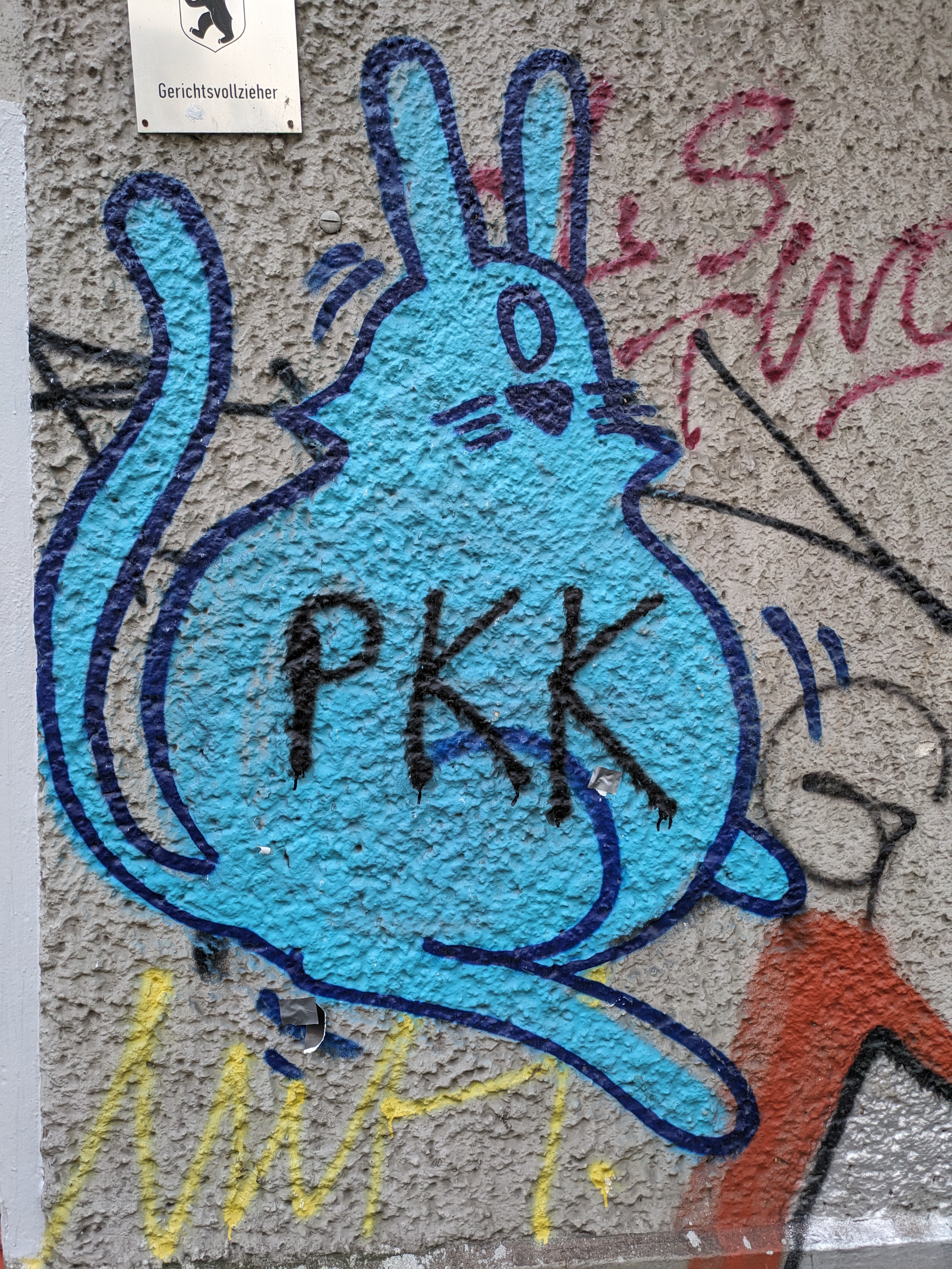 fat rabbit with one eye, sprayed with dark blue outline und cyan fill. "PKK" written ov the rabbits belly with black spray paint and probably by another person.