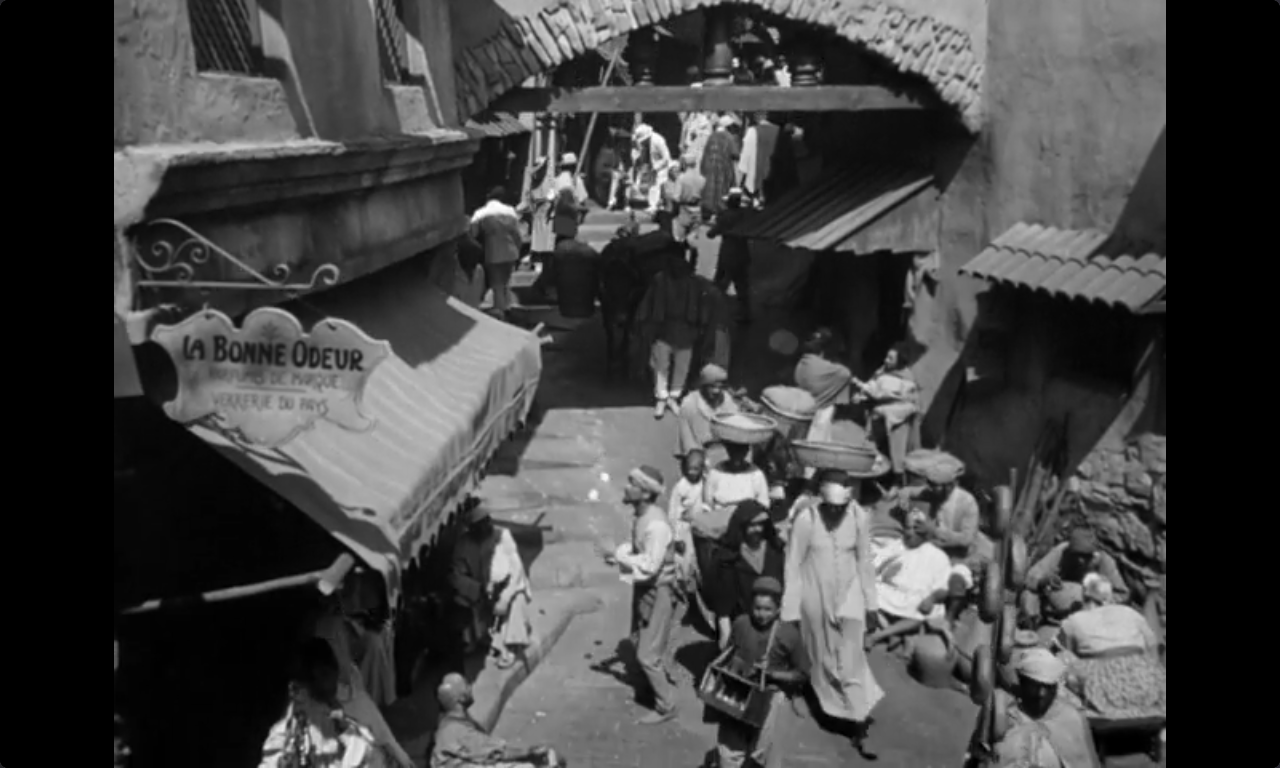 A still image from the movie Casablanca (1942). It is of a busy street in the town of Casablanca. Among the many people in the street, one man is juggling 3 balls.