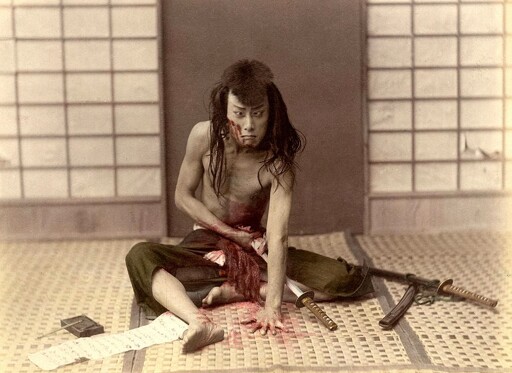 a japanese samurai demonstrates harakiri to the photographer using pig intestines.