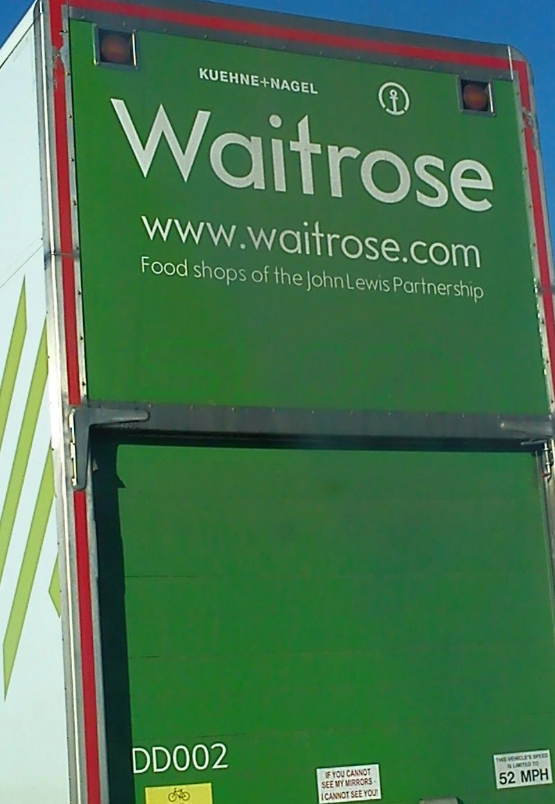 A Waitrose truck on which somebody has written the word "SLOGAN" in the dirt.