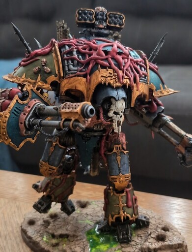 Nurgle possessed Chaos Knight Ruinator model from Games Workshop.  The giant robot is painted with a mix of turquoise and putrid green armor panels accented by dirty copper trim.  Tentacles and fleshy bits extrude from ports and gear interfaces in a sickly purple/pink hue.  A bone mask leers from the robot's head unit.
